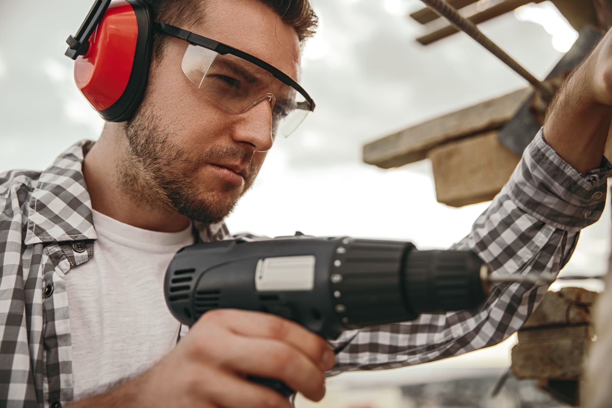 Builder working with drill on construction site