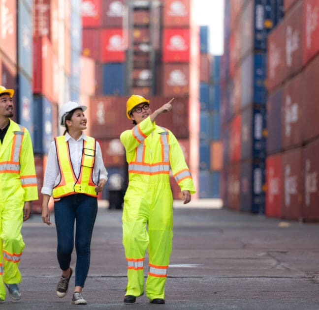 Group of engineers working with laptop in the container yard. This is a freight transportation and distribution warehouse.